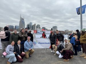 Lifepoint Health employees pose in front of banner at Special Olympics Tennessee Polar Plunge event